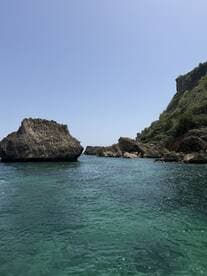 A stunning view of rocky formations along a clear turquoise coastline, perfect for showcasing the natural beauty of the area.