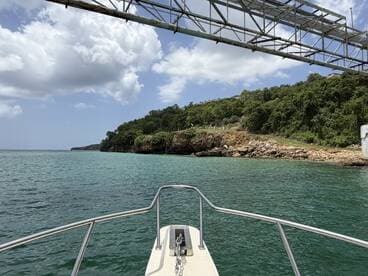 A scenic view from the bow of a boat, showcasing the lush coastline and clear turquoise waters, perfect for exploring beautiful destinations.