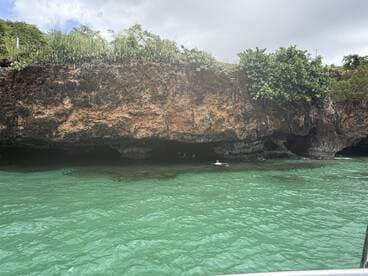 A scenic view of swimmers exploring a cave in clear turquoise waters, showcasing the beauty of the natural landscape and adventure on the water.