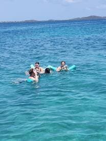 A lively group enjoys swimming in crystal-clear waters, showcasing the fun and excitement of water activities during their boating adventure.