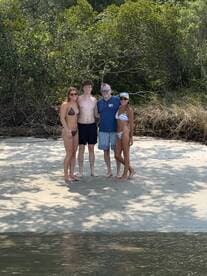 A cheerful group poses on the beach, enjoying a sunny day by the water — perfect for memorable beach outings and celebrations.