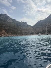 A stunning view of a secluded cove surrounded by rocky hills and crystal-clear waters, perfect for exploring hidden gems by boat.