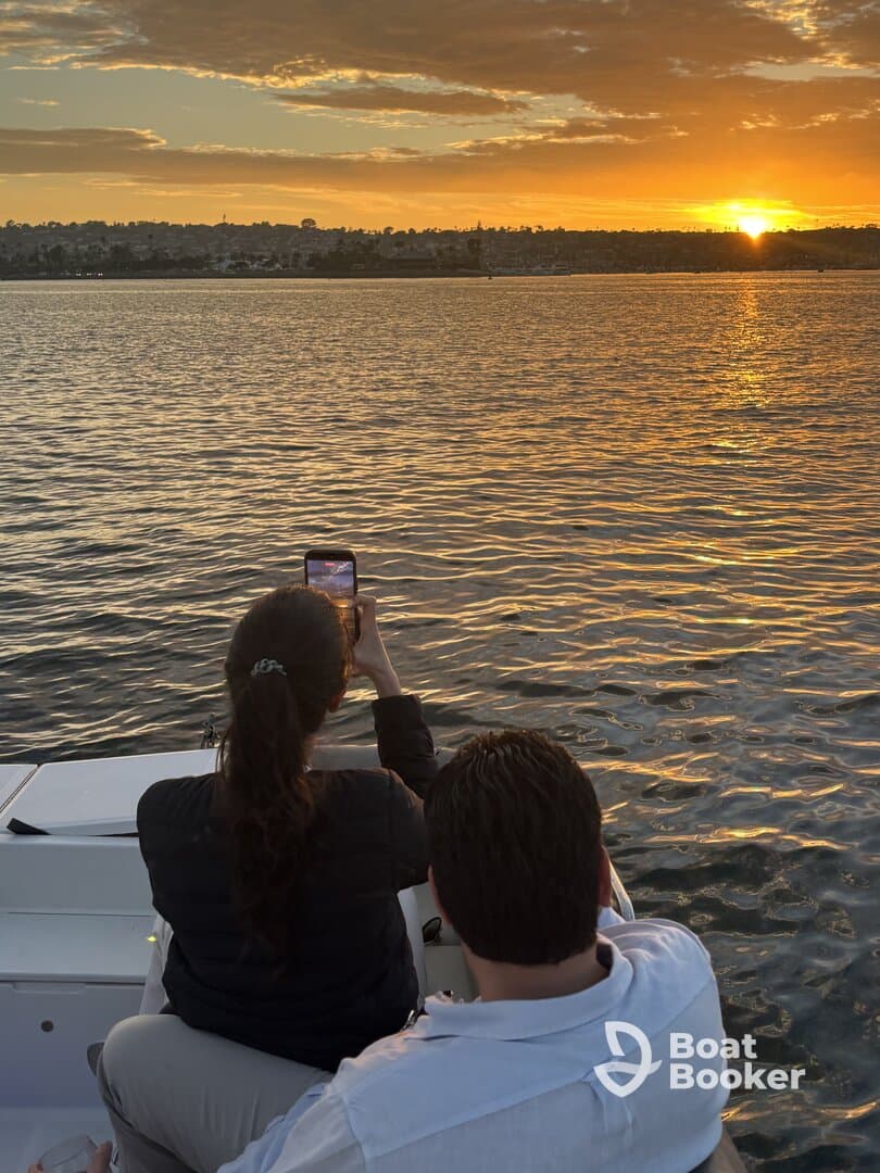 A couple captures the stunning sunset while enjoying a romantic moment on their boat — perfect for memorable evening cruises.