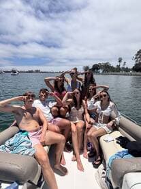 A lively group of friends poses for a fun photo on a boat, showcasing a perfect day of celebration and camaraderie on the water.