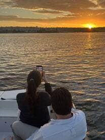 A couple captures the stunning sunset while enjoying a romantic moment on their boat — perfect for memorable evening cruises.