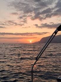 A serene sunset view from a boat, showcasing the vibrant colors of the sky reflecting on the water — perfect for romantic evening cruises.