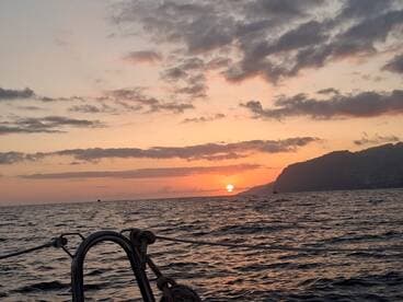 A serene sunset view from a boat, showcasing the tranquil ocean and distant coastline — perfect for romantic evening cruises.