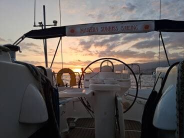 A serene view of the helm area aboard a sailing vessel, showcasing the beautiful sunset over the water — perfect for a relaxing sailing experience.