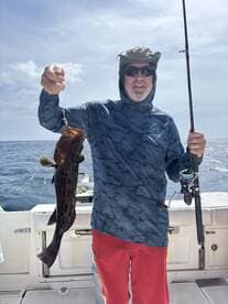 An angler proudly displays his catch while fishing on a boat, showcasing the thrill of deep-sea fishing adventures.