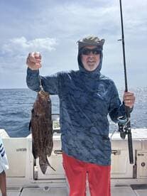 A man proudly displays his catch while fishing on a boat, showcasing the thrill of a successful day on the water.
