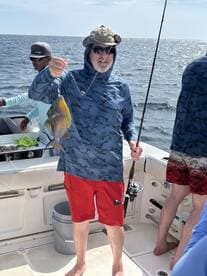 A proud angler displays his catch while fishing aboard a boat, showcasing the excitement of a day on the water with friends.