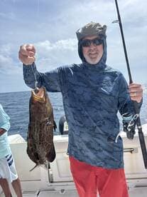 A proud angler holds up a freshly caught fish while fishing on the open ocean, showcasing the thrill of a successful day on the water.