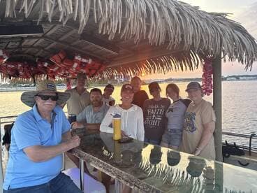 A cheerful group of friends gathers on a boat during sunset, enjoying each other's company and the beautiful waterfront view — perfect for memorable outings and celebrations.