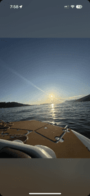 A serene sunset view from the deck of a boat, showcasing the tranquil waters and distant hills — perfect for peaceful evening cruises.