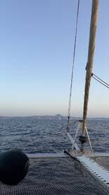 A serene view from the deck of a catamaran, showcasing the vast ocean and distant hills, perfect for sailing enthusiasts and scenic adventures.