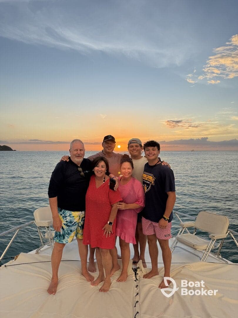 A joyful family gathers for a sunset photo on a boat, capturing a memorable moment together against a stunning ocean backdrop.