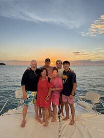 A joyful family gathers for a sunset photo on a boat, capturing a memorable moment together against a stunning ocean backdrop.