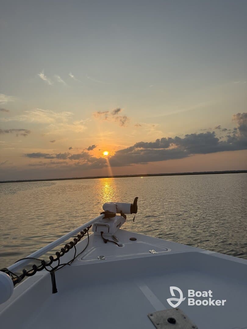 A serene sunset view from the bow of a boat, showcasing the tranquil waters and vibrant sky — perfect for evening cruises.