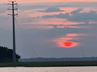 A sunset view with a power line in the foreground, creating an unclear composition.