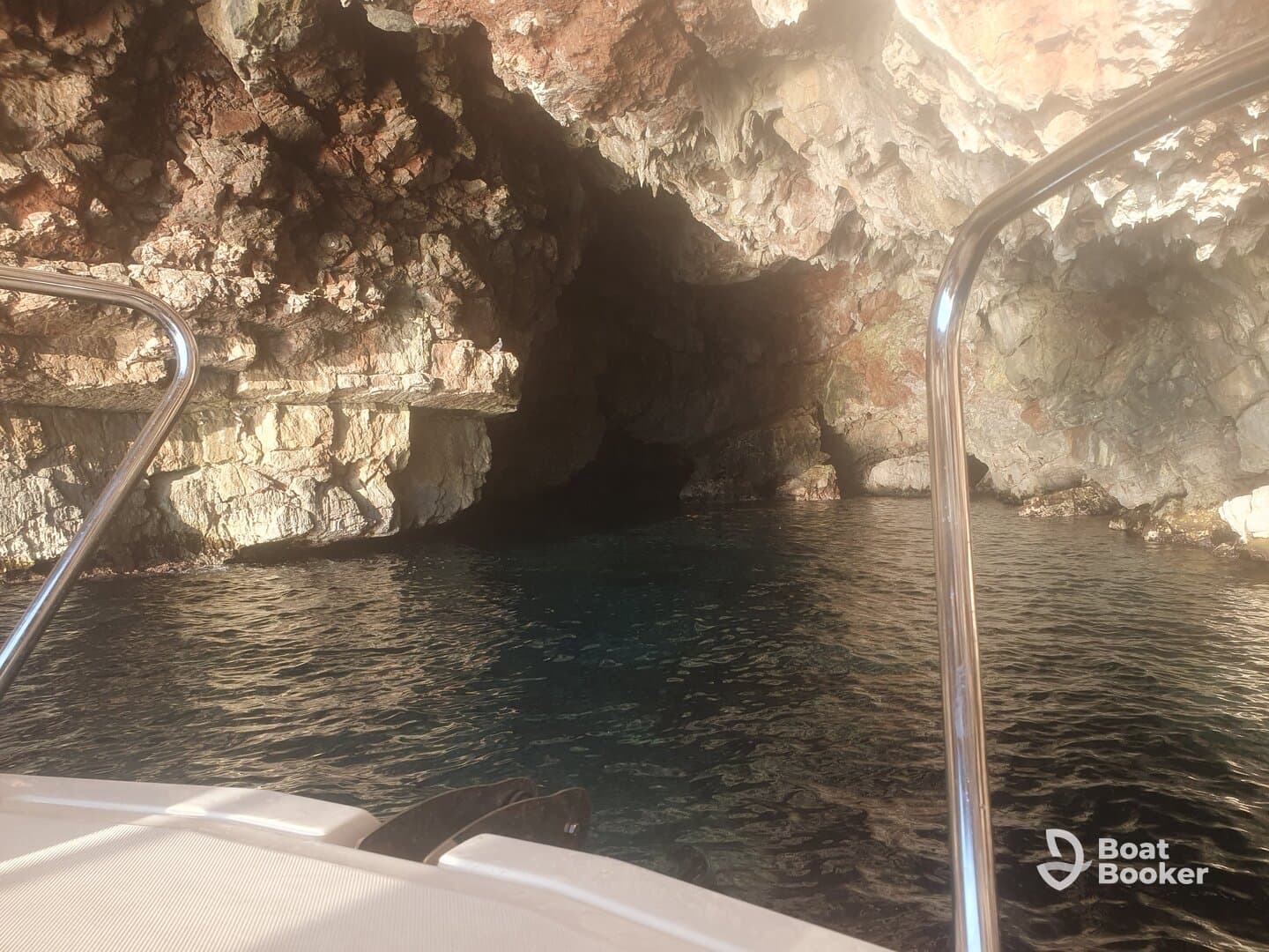 A stunning view of a rocky cave entrance from the deck of a boat, showcasing the serene waters and natural beauty of the surroundings.