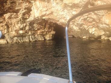 A scenic view of a rocky coastline with a cave entrance, captured from a boat — perfect for exploring hidden gems along the shore.