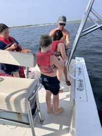 A family prepares for a fun day on the water, ensuring safety with life jackets aboard their boat. Perfect for memorable boating adventures and family outings.