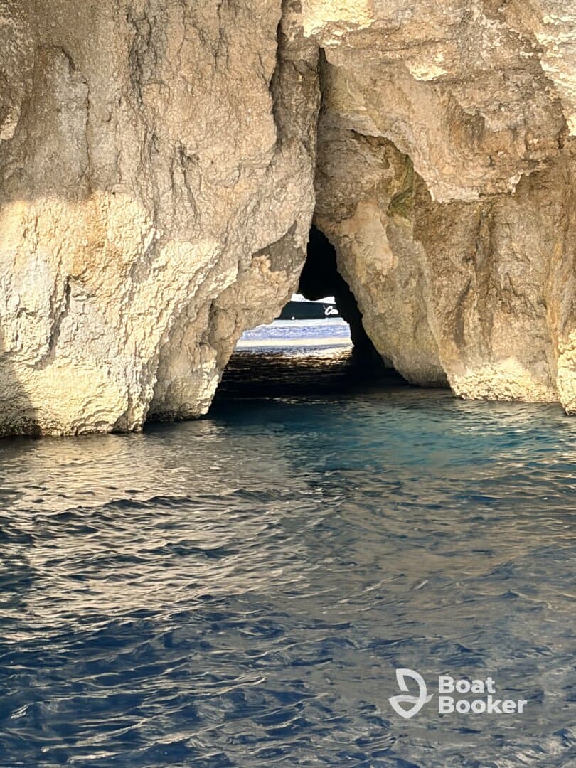 A stunning view of a cave opening with a boat visible in the background, showcasing the natural beauty of the coastline — perfect for adventure seekers exploring hidden gems.