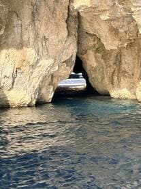 A stunning view of a cave opening with a boat visible in the background, showcasing the natural beauty of the coastline — perfect for adventure seekers exploring hidden gems.
