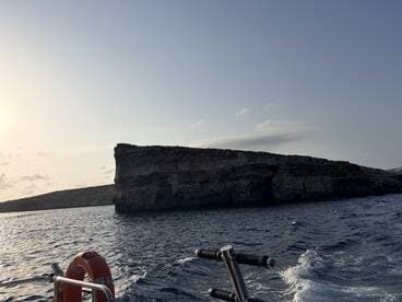 A stunning view of a rocky coastline at sunset, showcasing the natural beauty of the area — perfect for scenic boat tours and exploration.