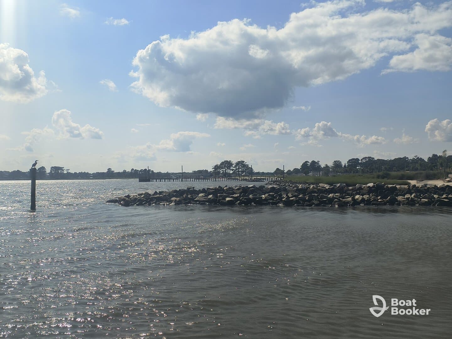 A scenic view of a waterfront with a pier and a bird perched on a post, capturing the tranquil atmosphere of the area.