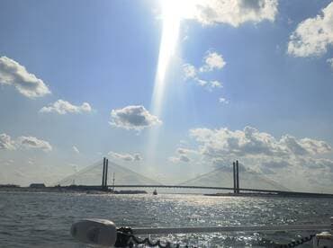 A stunning view of a bridge over shimmering waters, illuminated by sunlight — a perfect representation of a scenic boating experience.