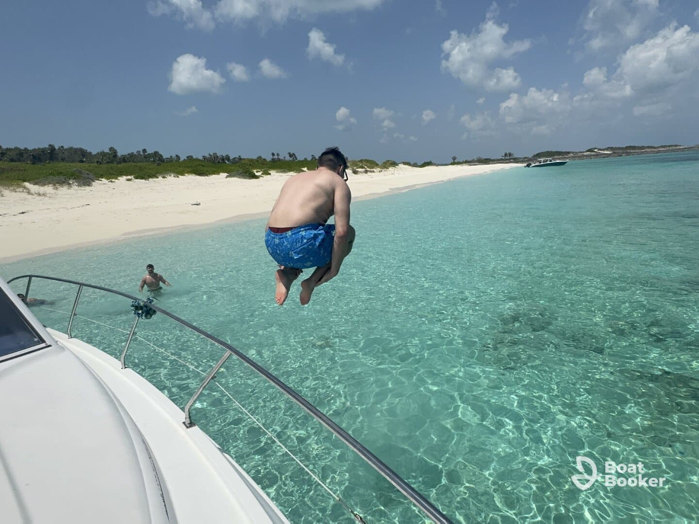 A thrilling moment captured as a person jumps off the boat into the crystal-clear waters, with a beautiful beach backdrop — perfect for summer adventures and water fun.