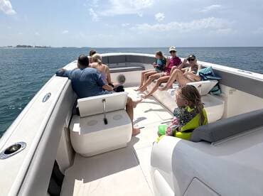 A joyful group of family and friends relaxes on a boat under the sun, enjoying a perfect day on the water. Ideal for family outings and group adventures.