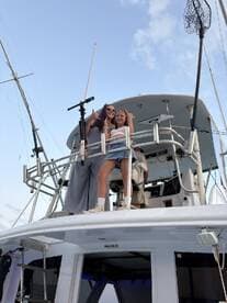 Two girls pose joyfully on the deck of a boat, capturing a fun moment at sea — perfect for family adventures or group outings.