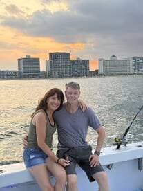 A couple enjoys a romantic moment on a fishing boat at sunset, capturing the essence of a perfect day on the water.