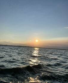 A stunning sunset over the water, with shimmering reflections creating a picturesque scene — perfect for romantic evenings or tranquil boat rides.