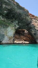 Swimmers enjoy the stunning turquoise waters near a natural cave, creating a picturesque backdrop for a memorable boating adventure.