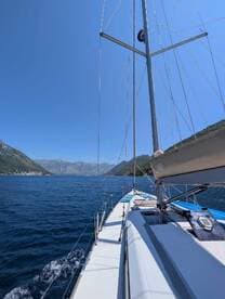 A stunning view of a sailboat navigating through calm waters, surrounded by majestic mountains — perfect for sailing enthusiasts and scenic adventures.
