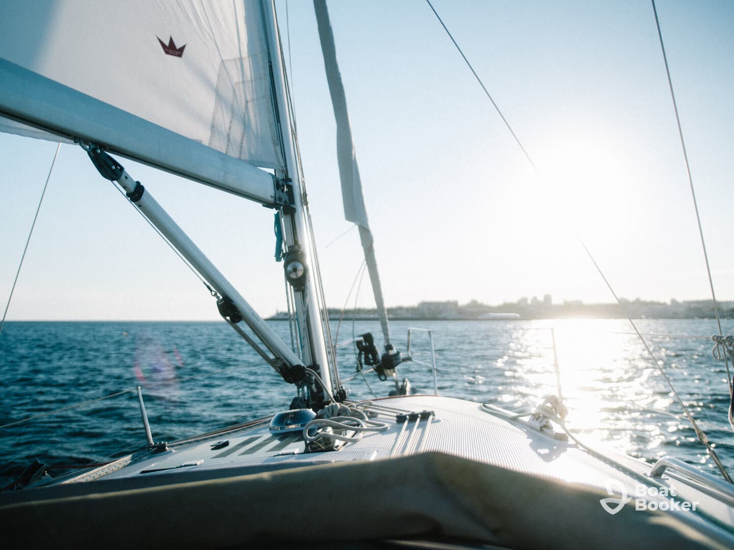 A stunning view from the deck of a sailboat, capturing the serene waters and the sun reflecting off the surface — perfect for sailing enthusiasts and sunset lovers.