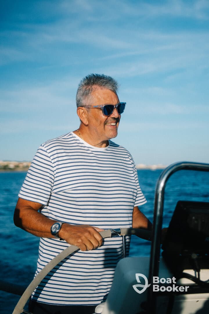 A man enjoys steering a boat under a clear blue sky, capturing the essence of a perfect day on the water.