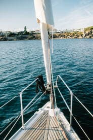A stunning view from the bow of a sailboat, showcasing the vessel's sleek design against a backdrop of calm waters and coastal scenery.