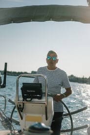 A man navigates a sailboat, showcasing the joy of sailing on open waters. Perfect for adventure seekers and sailing enthusiasts.