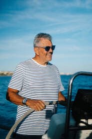 A man enjoys steering a boat under a clear blue sky, capturing the essence of a perfect day on the water.
