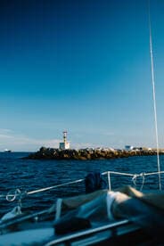 A picturesque view of a lighthouse at the harbor, captured from a boat, showcasing the serene beauty of coastal navigation.