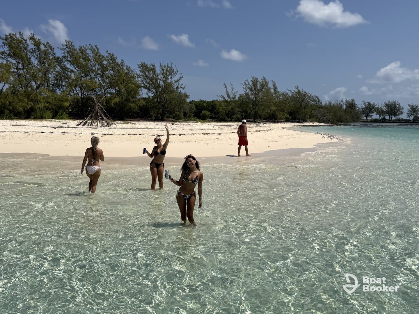 A lively group enjoys a sunny day at the beach, wading in crystal-clear waters while celebrating with drinks — a perfect tropical getaway.