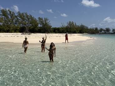 A lively group enjoys a sunny day at the beach, wading in crystal-clear waters while celebrating with drinks — a perfect tropical getaway.