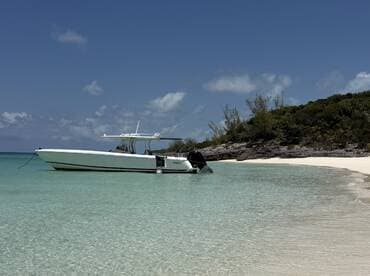 A sleek speedboat anchored in crystal-clear turquoise waters, showcasing the perfect spot for a day of relaxation on the beach.