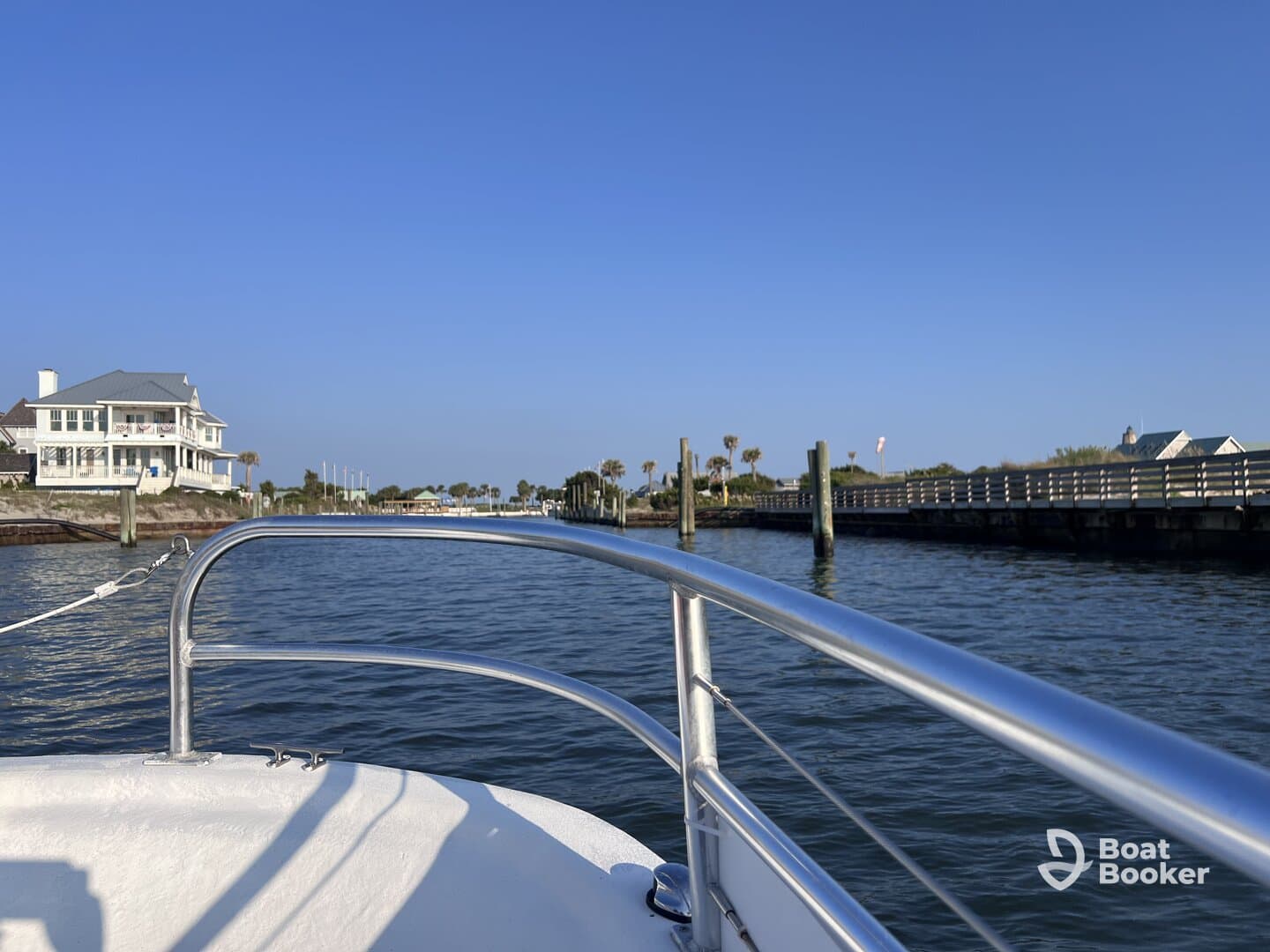 A view from the front of a boat navigating through a calm waterway, showcasing the scenic surroundings and nearby docked structures.