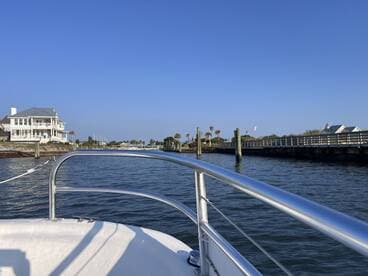 A view from the front of a boat navigating through a calm waterway, showcasing the scenic surroundings and nearby docked structures.