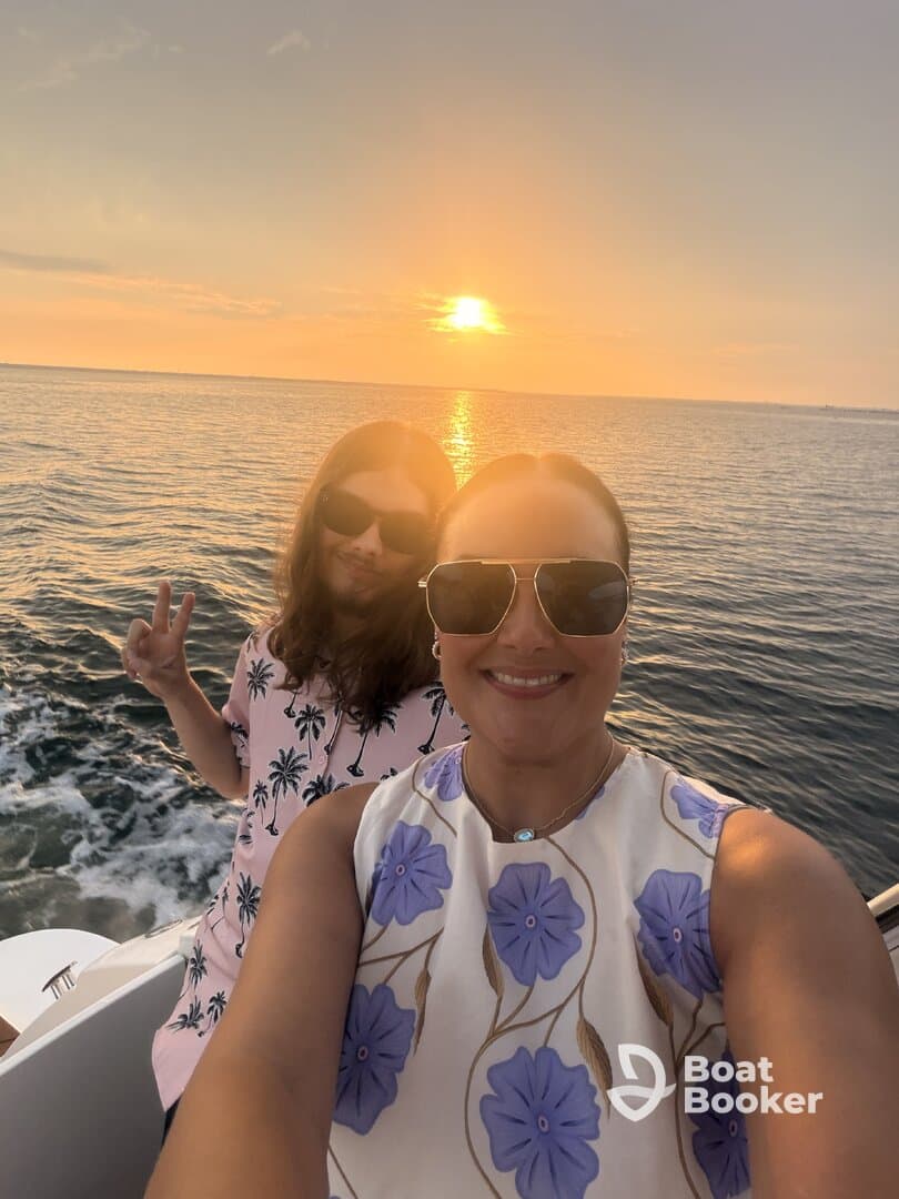 A joyful moment captured at sunset with two friends enjoying a boat ride, perfect for memorable outings and celebrations on the water.